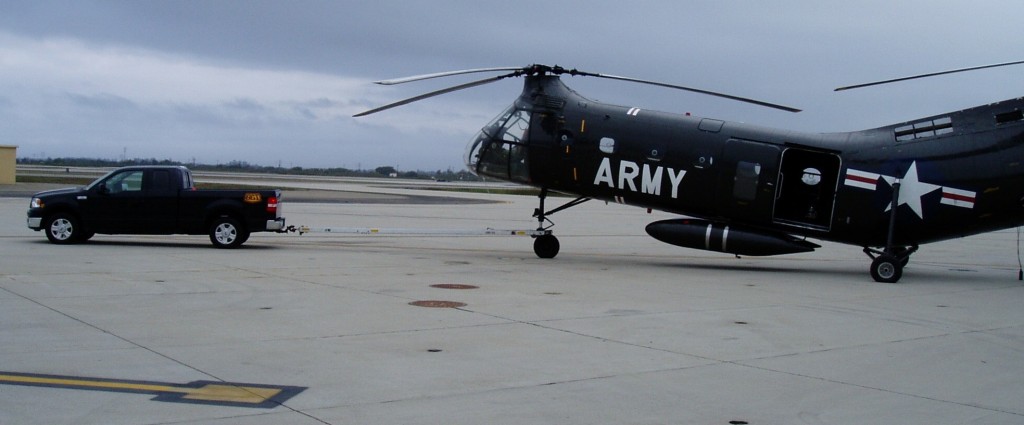 A Black Gold Industries pickup truck towing an Army helicopter